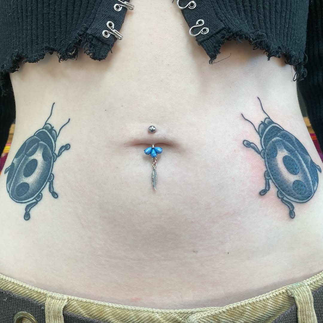 Matching black and grey ladybug tattoos on the stomach by Marshall